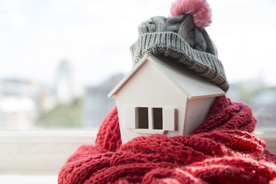 A small white house wrapped in a red scarf and a hat.