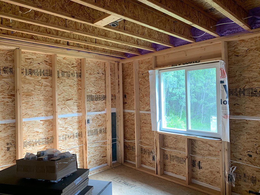 A room with wooden walls and a window in a house under construction.