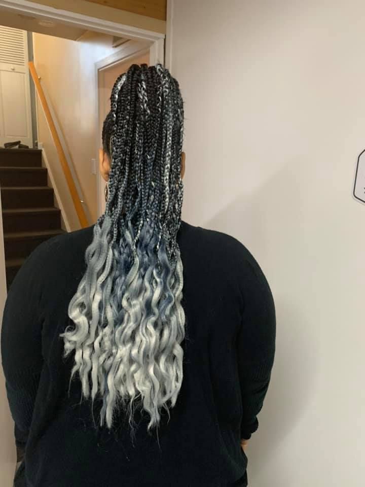 A woman with braids in her hair is standing in front of stairs.