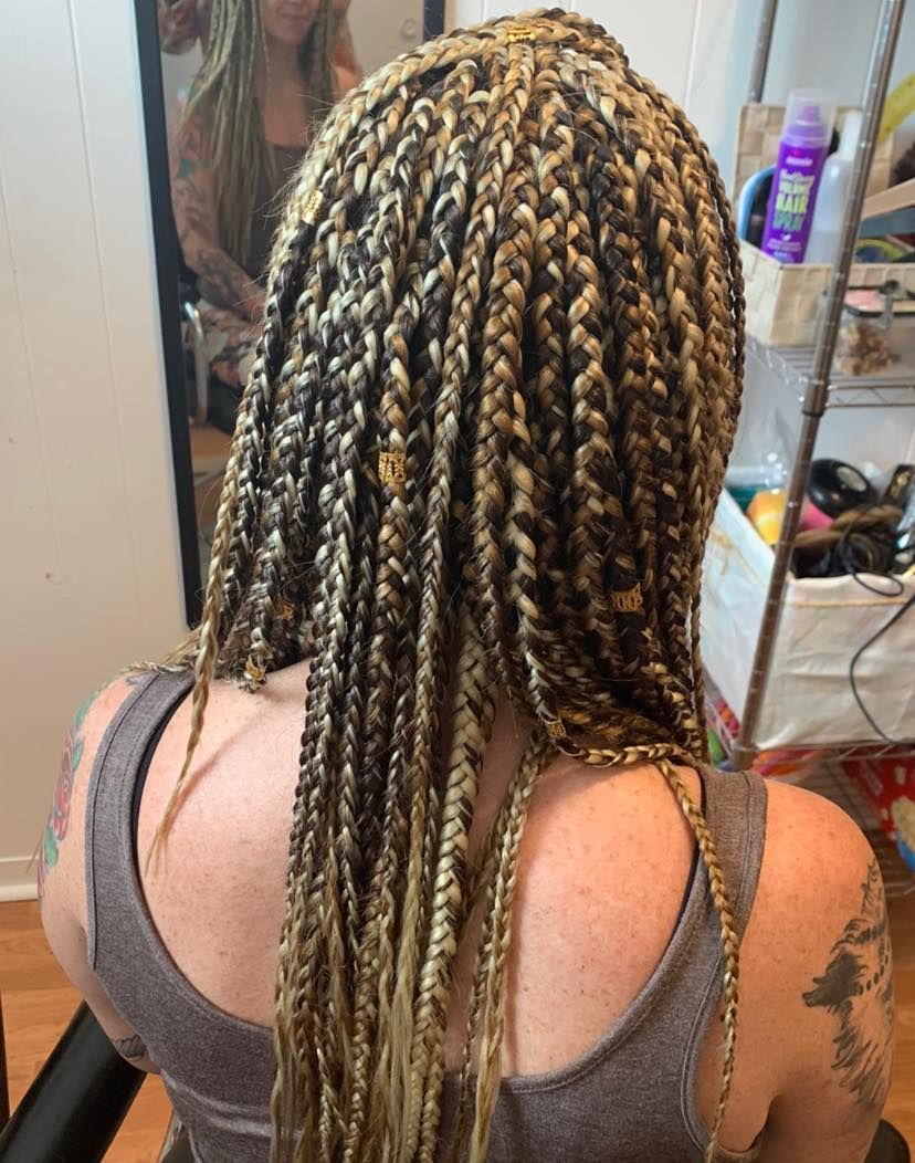 A woman with braids in her hair is sitting in front of a mirror.