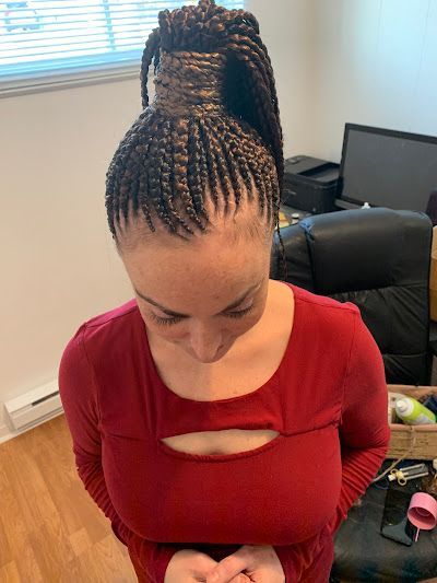 A woman with braids in her hair is wearing a red shirt.