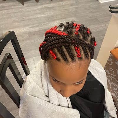 A little girl is sitting in a chair with braids in her hair.