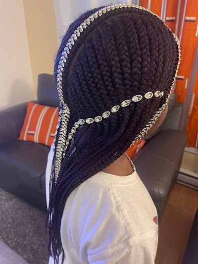 A woman with braids and pearls in her hair is standing in a living room.
