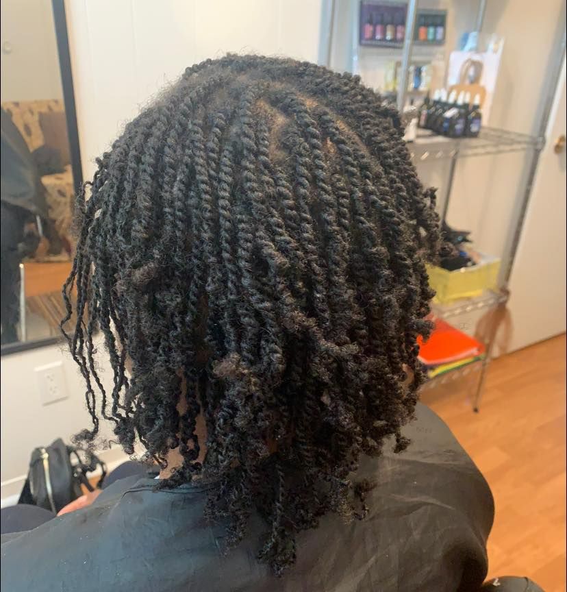 A woman with dreadlocks is sitting in a chair in front of a mirror.