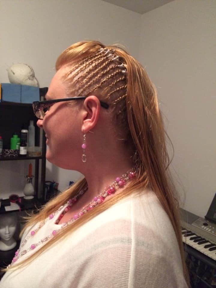 A woman wearing glasses and earrings is standing in front of a keyboard.