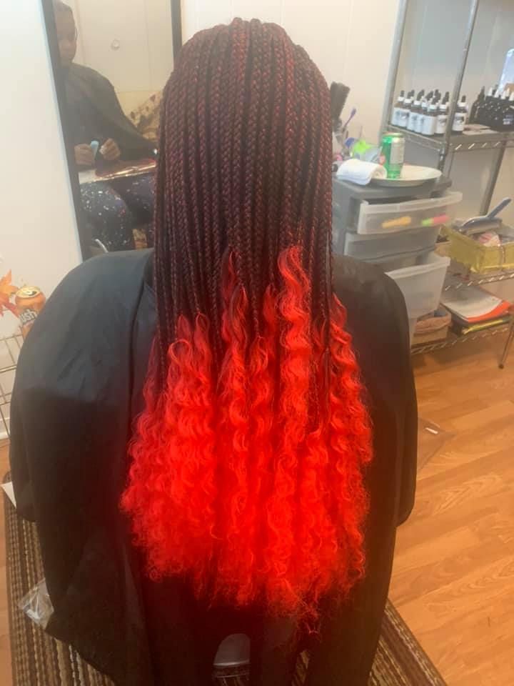 A woman with red braids is sitting in a chair in front of a mirror.