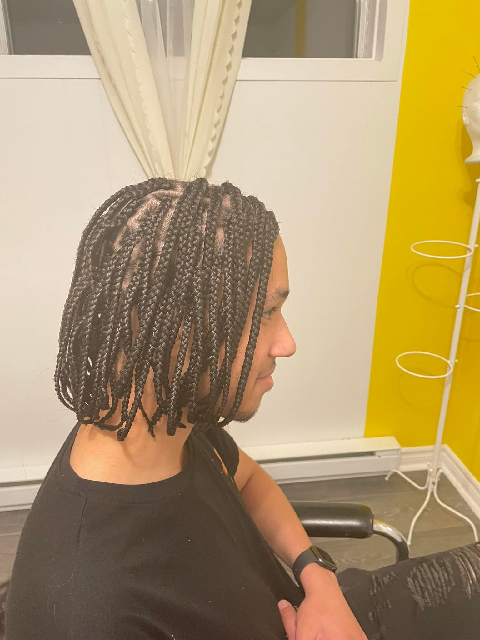 A man with braids in his hair is sitting in a chair.