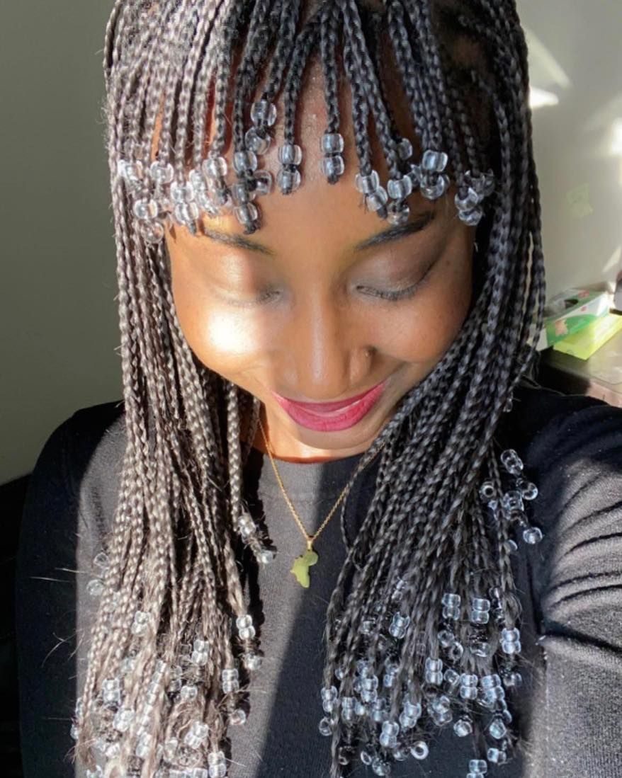 A woman with braids and a headband is taking a selfie.