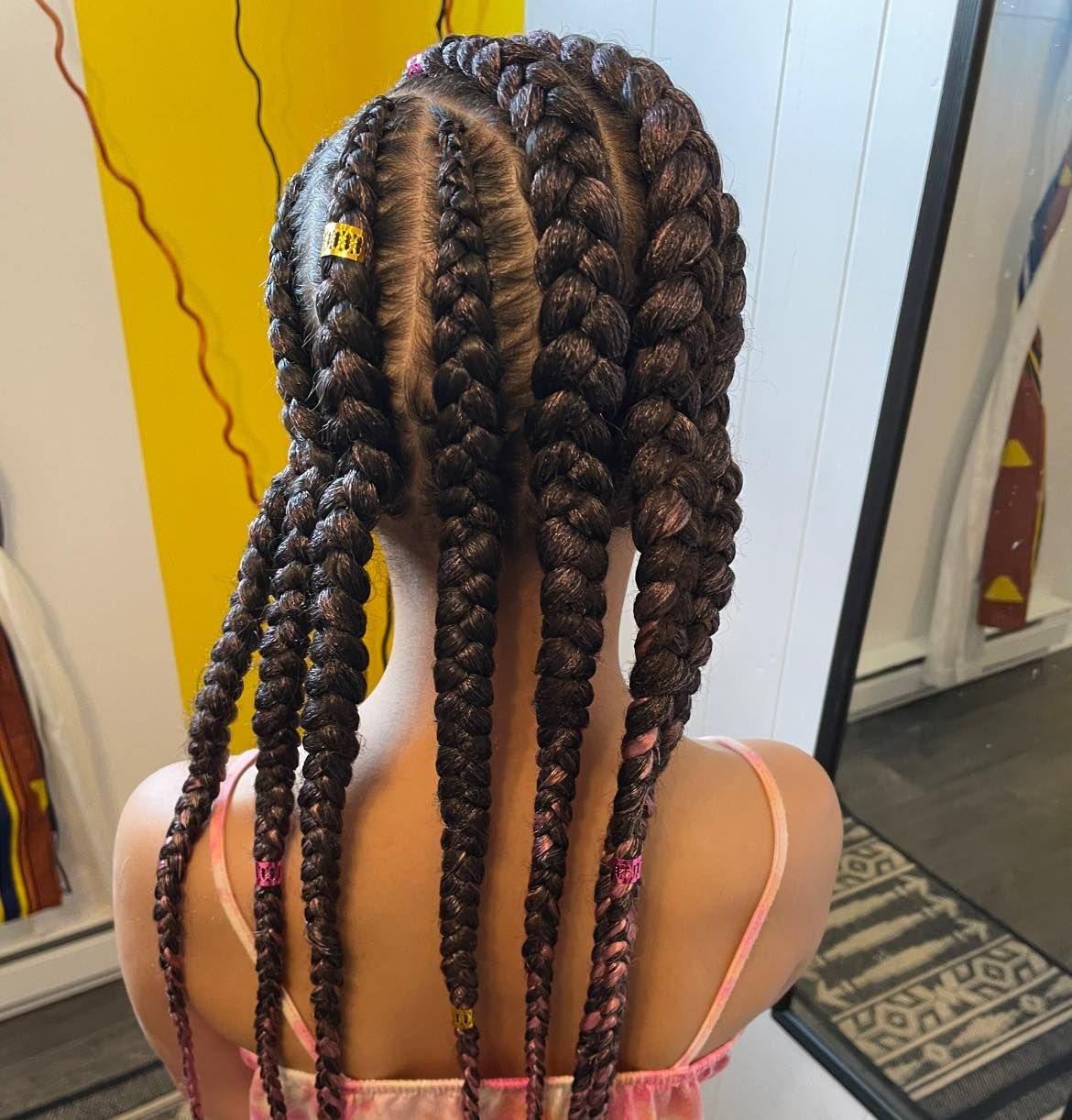 A girl with braids in her hair is wearing a pink tank top