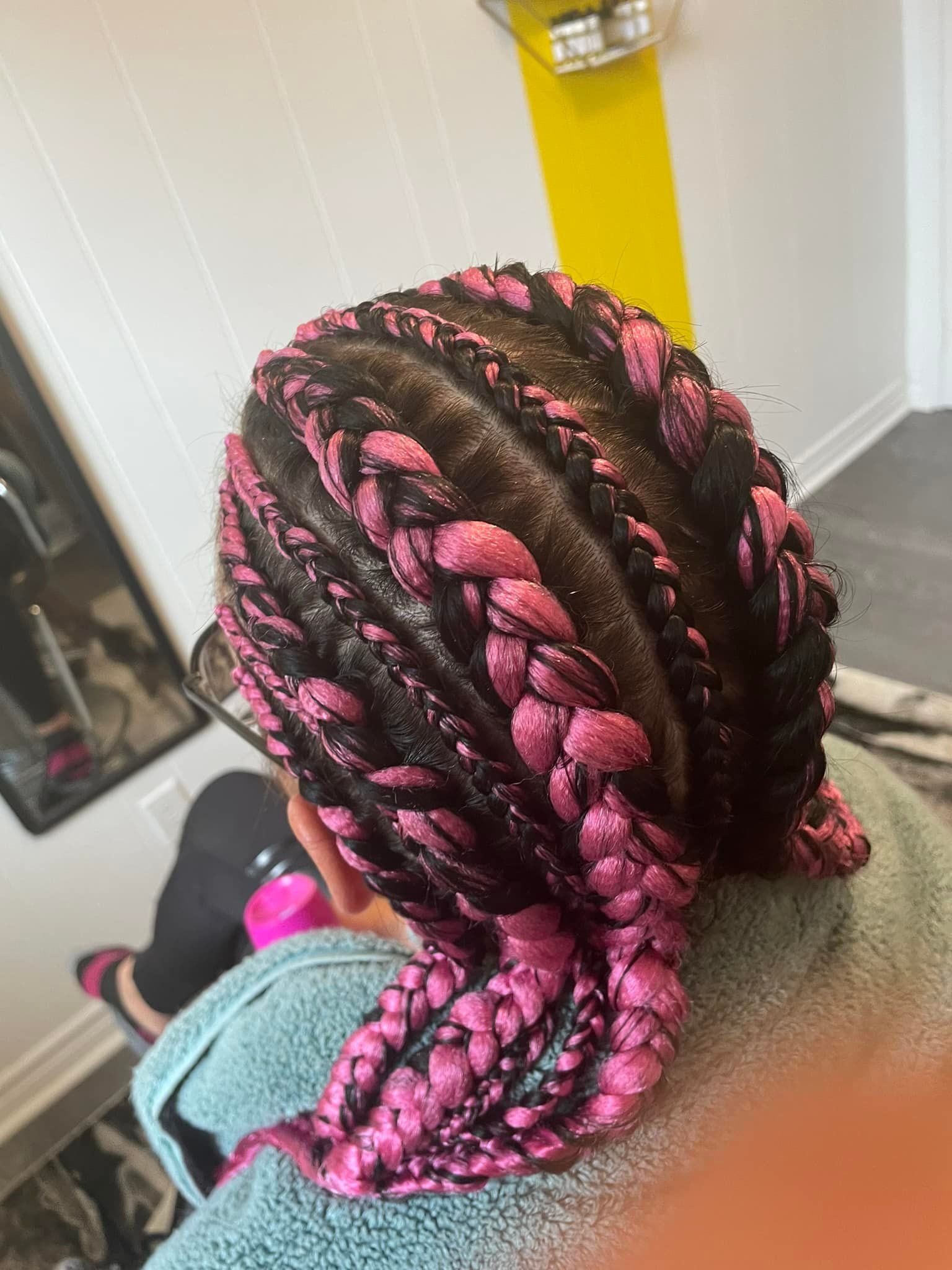 A woman with pink braids in her hair is sitting in a room.