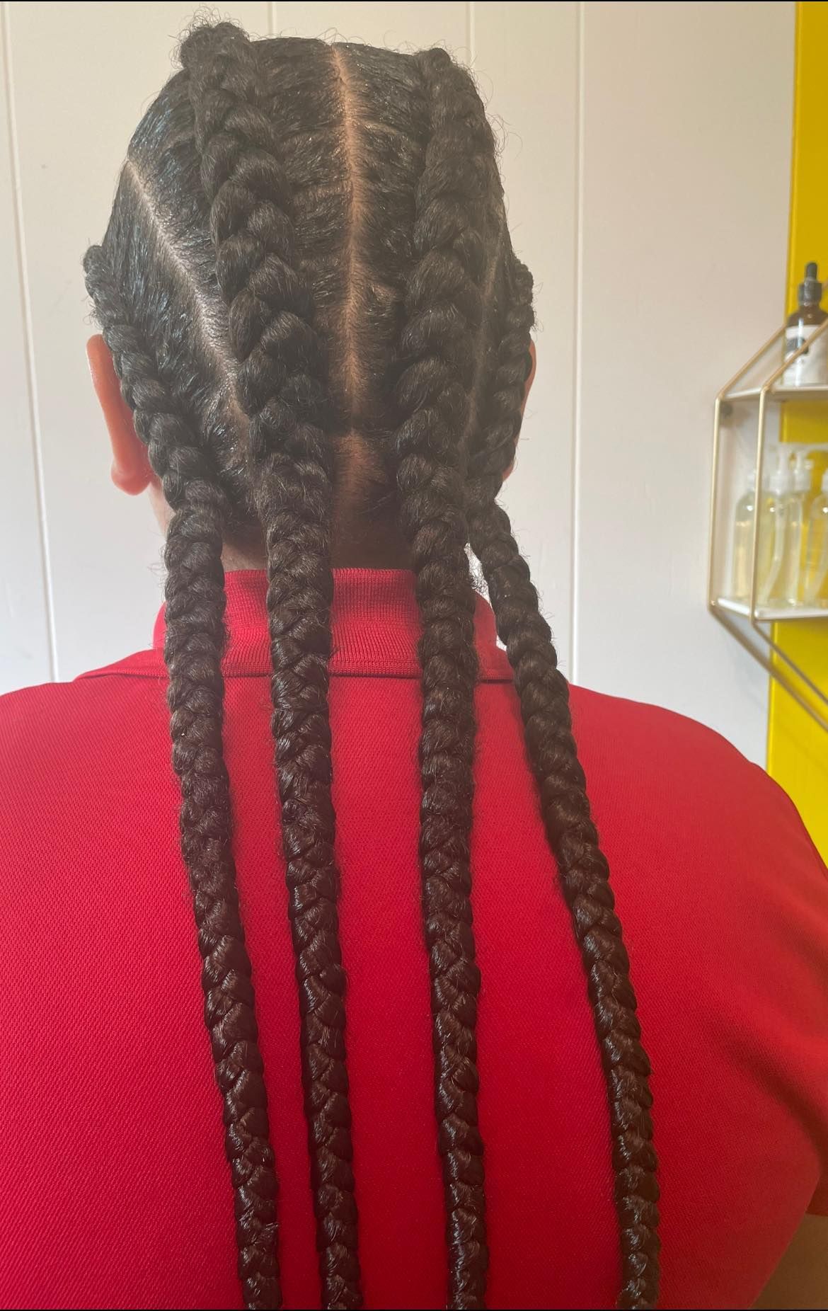 A woman with braids in her hair is wearing a red shirt.
