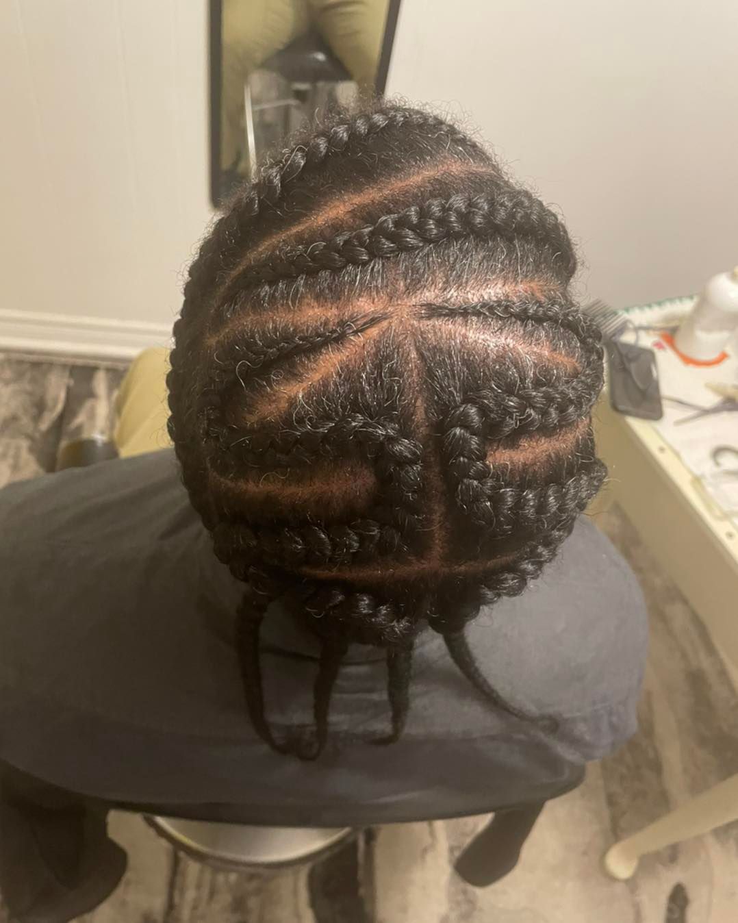 A person is sitting on a chair with their hair braided.