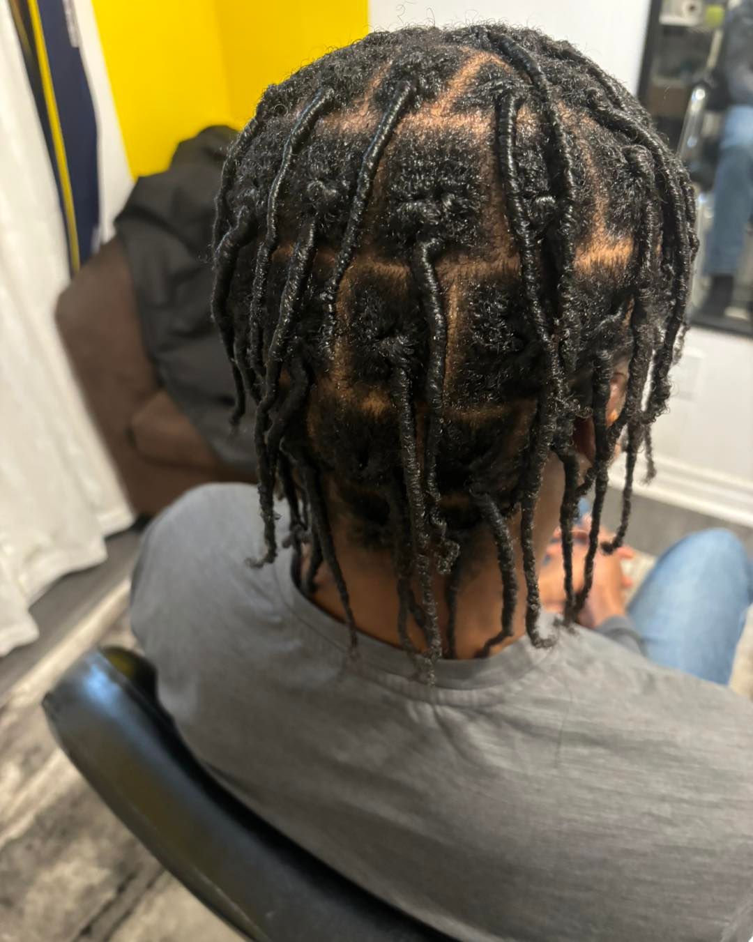 A man with dreadlocks is sitting in a chair with his back to the camera.