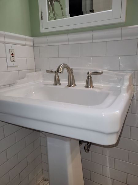 A bathroom sink with a pedestal and a mirror above it.