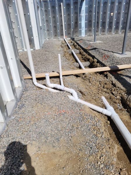 A bunch of pipes are laying in the dirt.