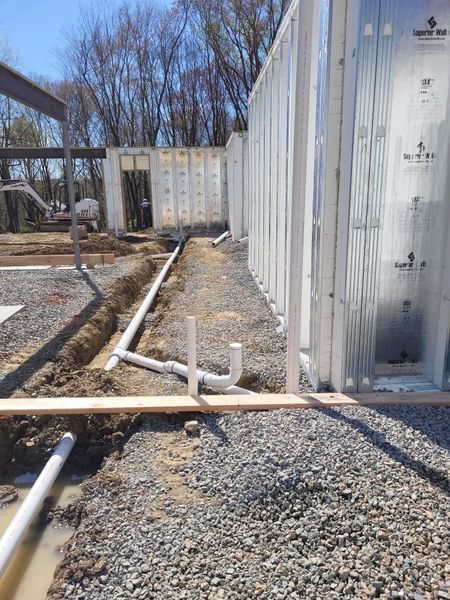 A building under construction with a lot of pipes in the ground.