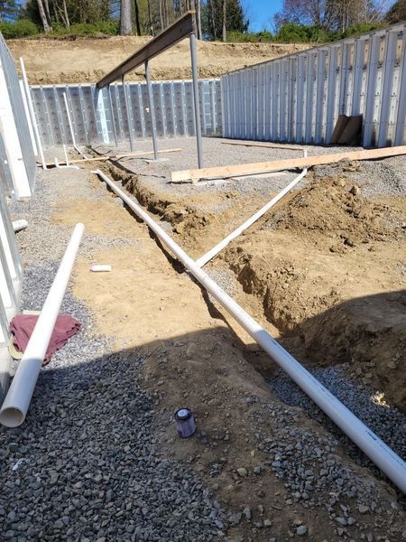 A bunch of pipes are laying in the dirt