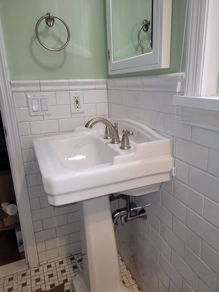 A bathroom with a pedestal sink and a mirror.