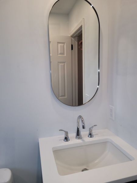 A bathroom with a sink , toilet and mirror.