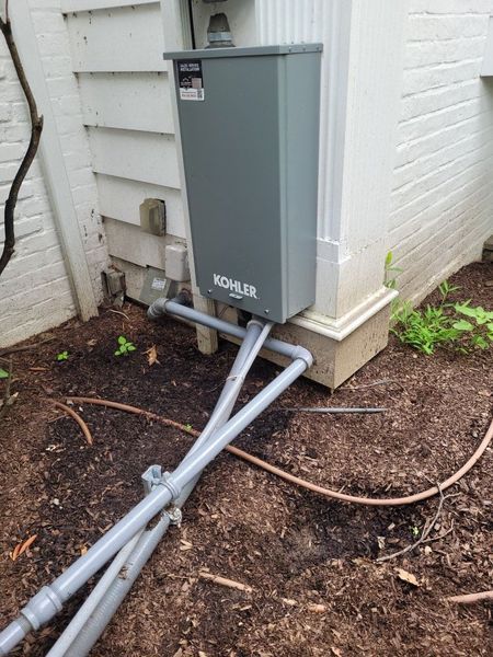 A kohler electrical box is sitting on the side of a house.