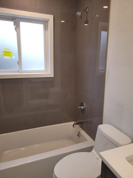 A bathroom with a tub , toilet , sink and window