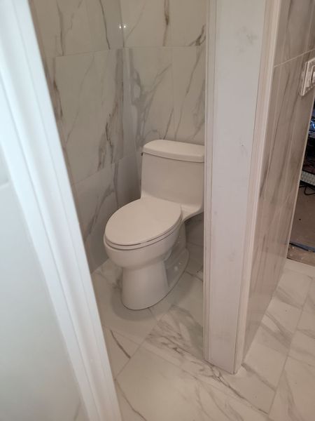 A toilet is sitting in a bathroom next to a door.