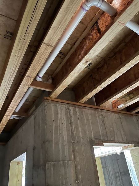 A room under construction with pipes coming out of the ceiling.