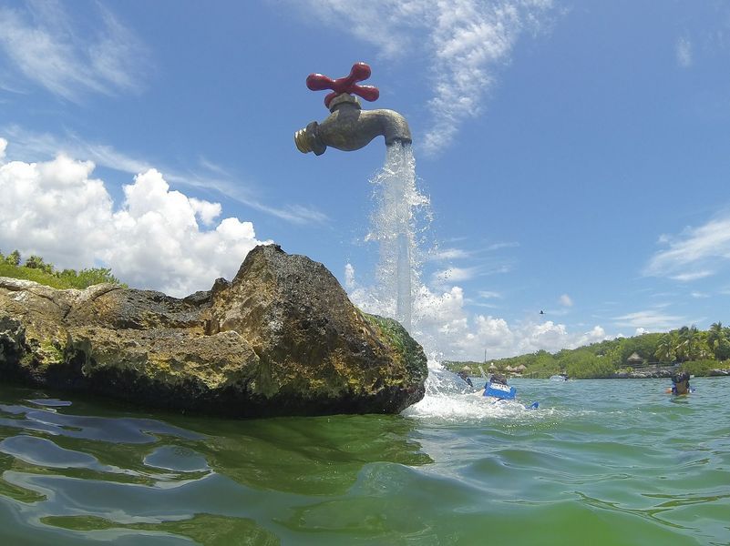 A faucet is spraying water from a rock in the ocean.