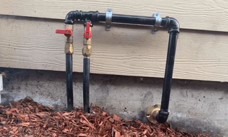 A couple of pipes sitting on top of a pile of mulch next to a house.