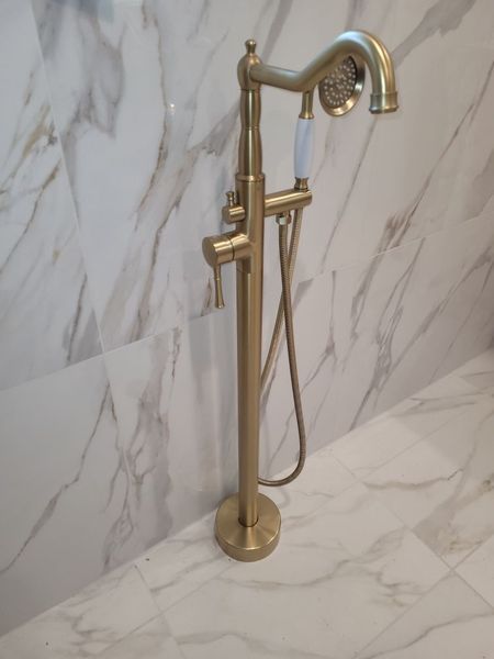 A gold bathtub faucet is sitting on a marble counter top.