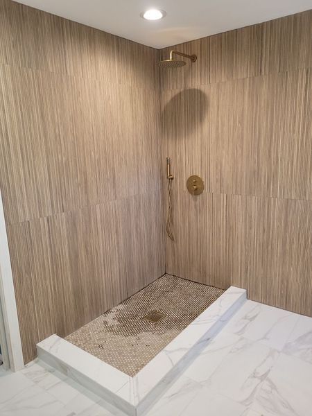 A bathroom with a walk in shower and a marble counter top.