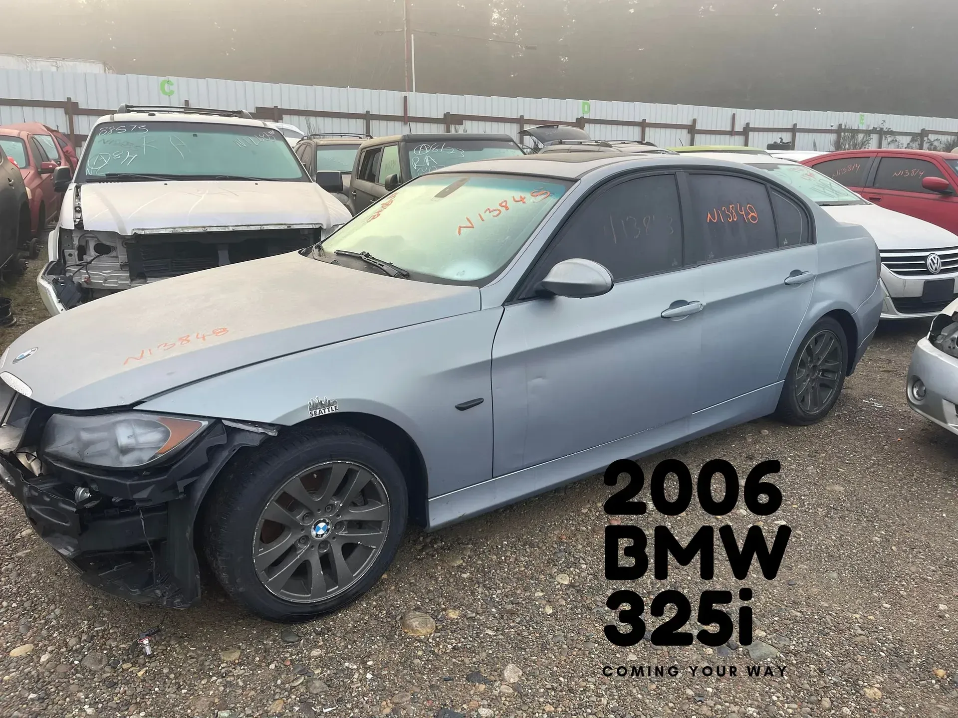 A damaged 2006 BMW 325i sedan in a salvage yard. Gray car with front-end damage and missing parts.