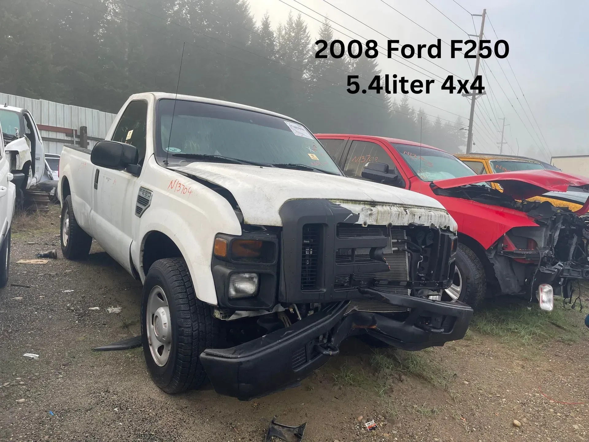 White 2008 Ford F250 pickup truck with front-end damage, in a junkyard setting.