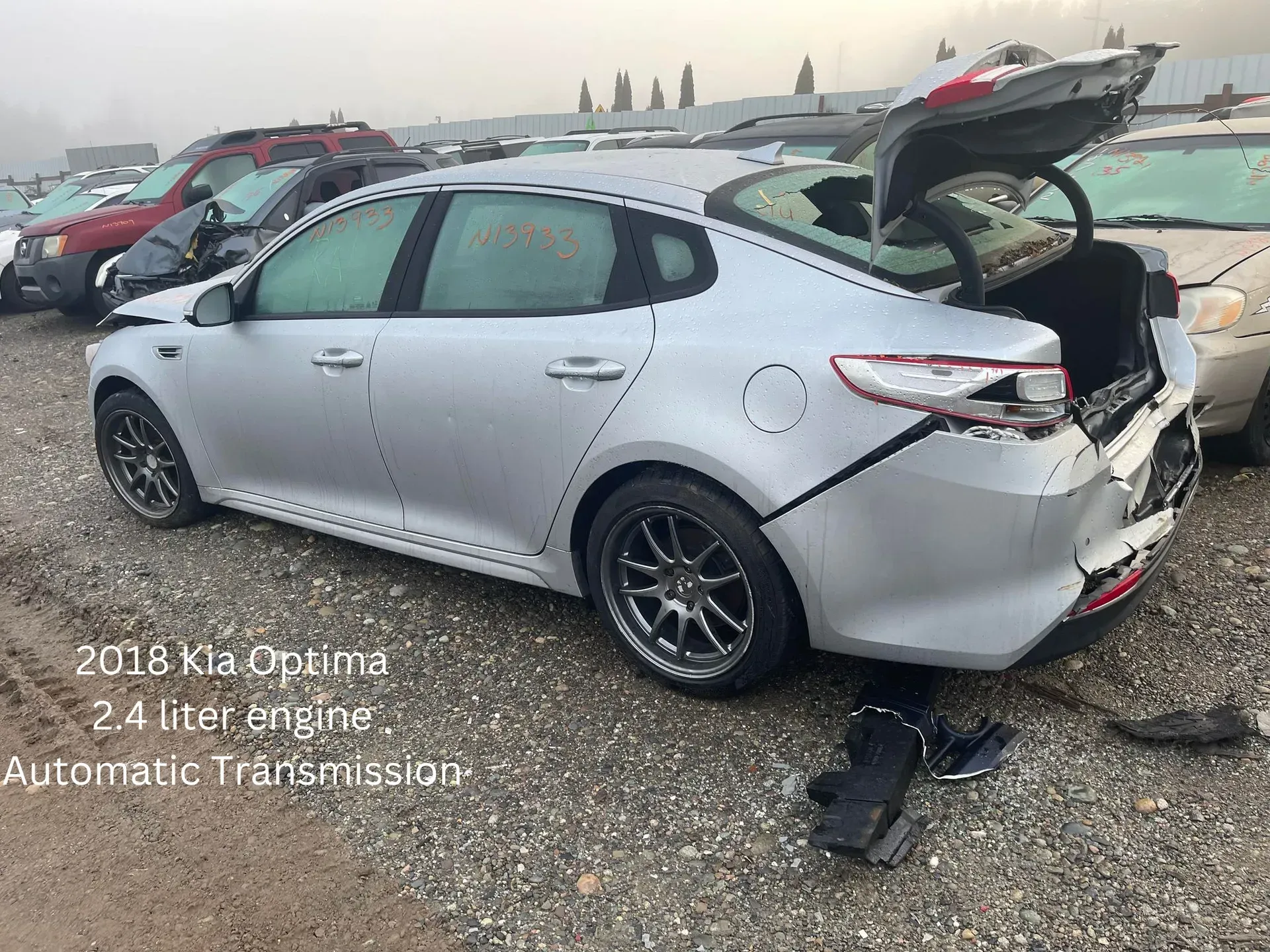 Silver 2016 Kia Optima damaged at a salvage yard with trunk open.