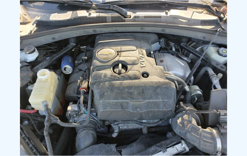 Dirty car engine, with various components and an open compartment. Dusty, with a blue can visible.