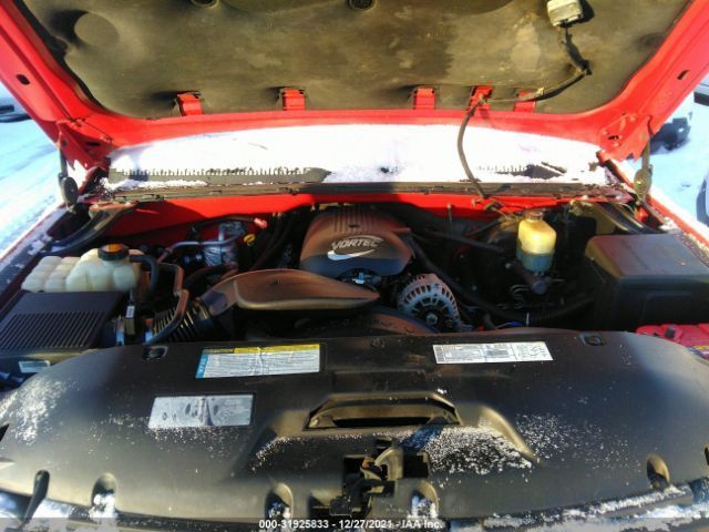 Red truck engine bay with snow; black engine cover, air intake, and fluid reservoirs.