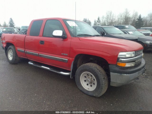 Red Chevrolet pickup truck with a flat front tire, parked outdoors.