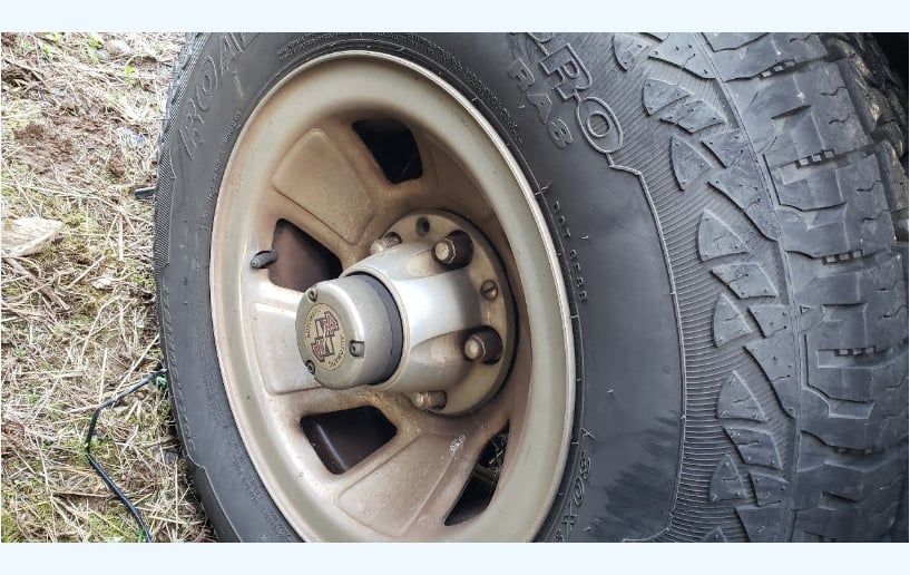 Close-up of a vehicle's tire and rim on a light brown wheel, with a rugged tread.