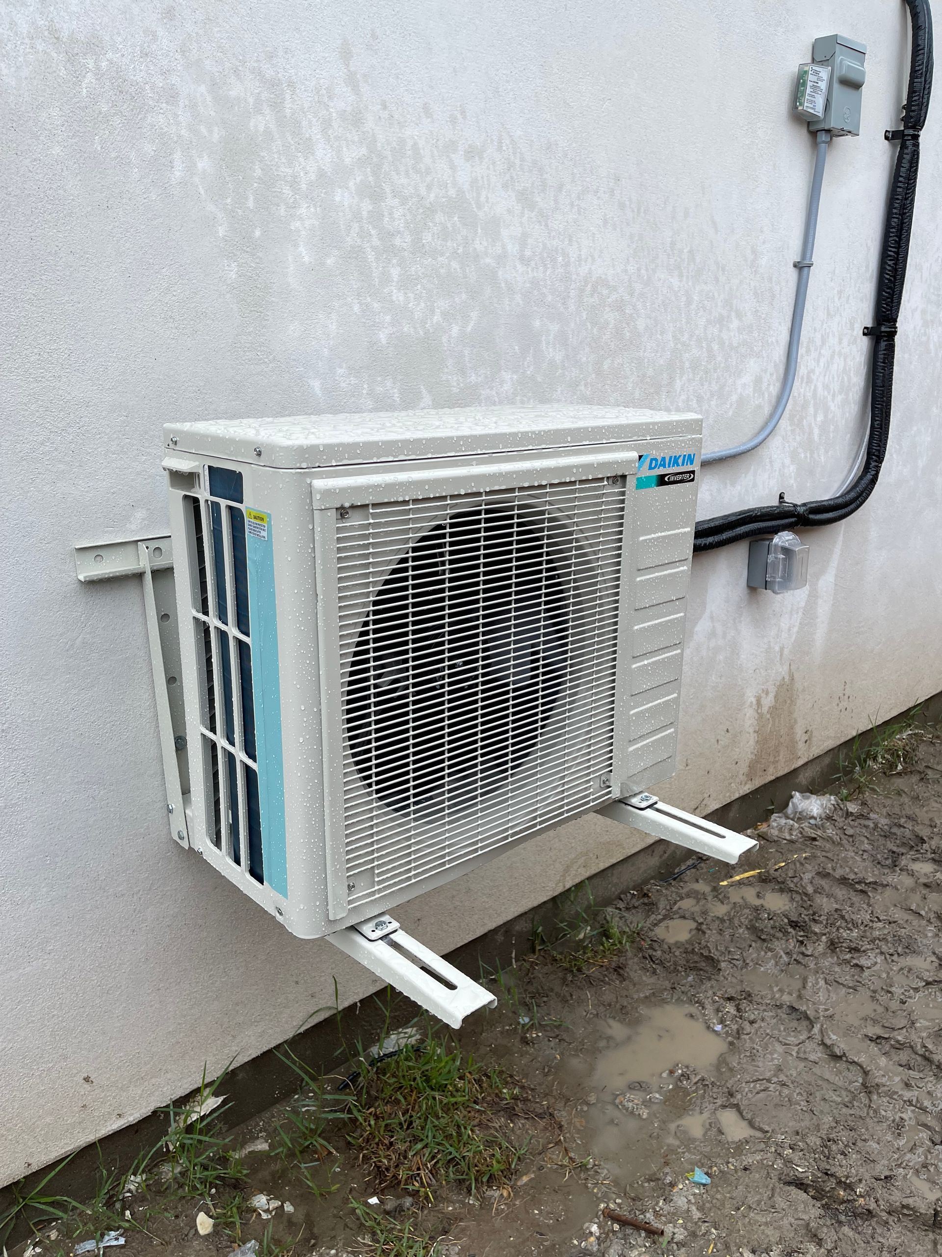 A white air conditioner is hanging from the ceiling in a room next to a window.