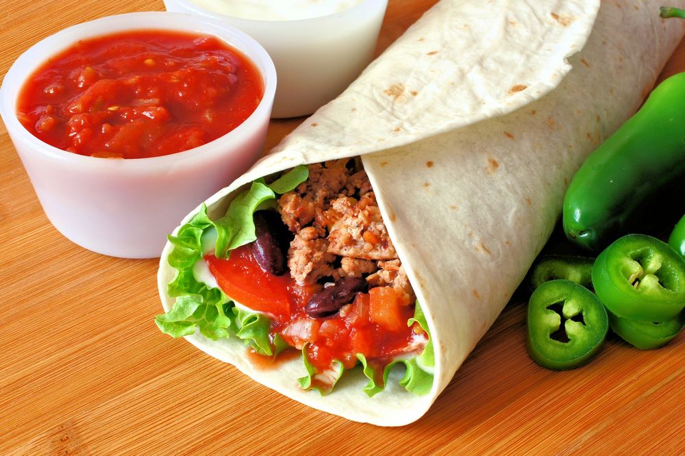 Una tortilla ripiena di carne e verdure con salsa e jalapeño