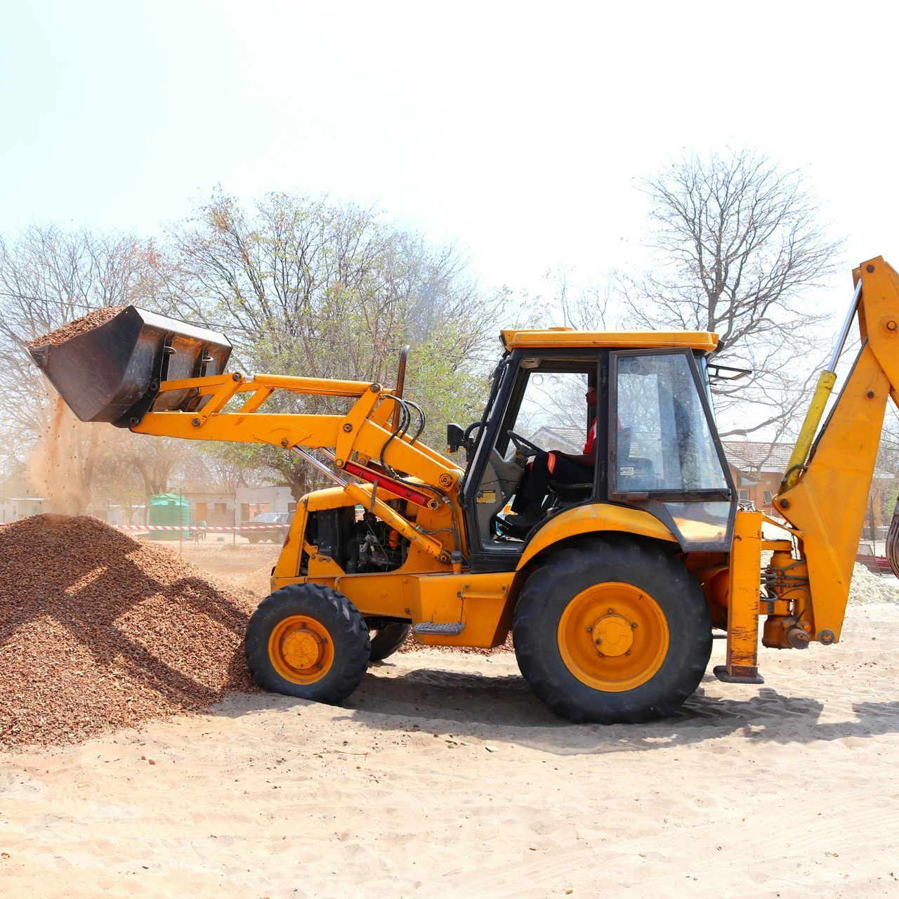Person with red curved paper head covering holding rock, purple hues.