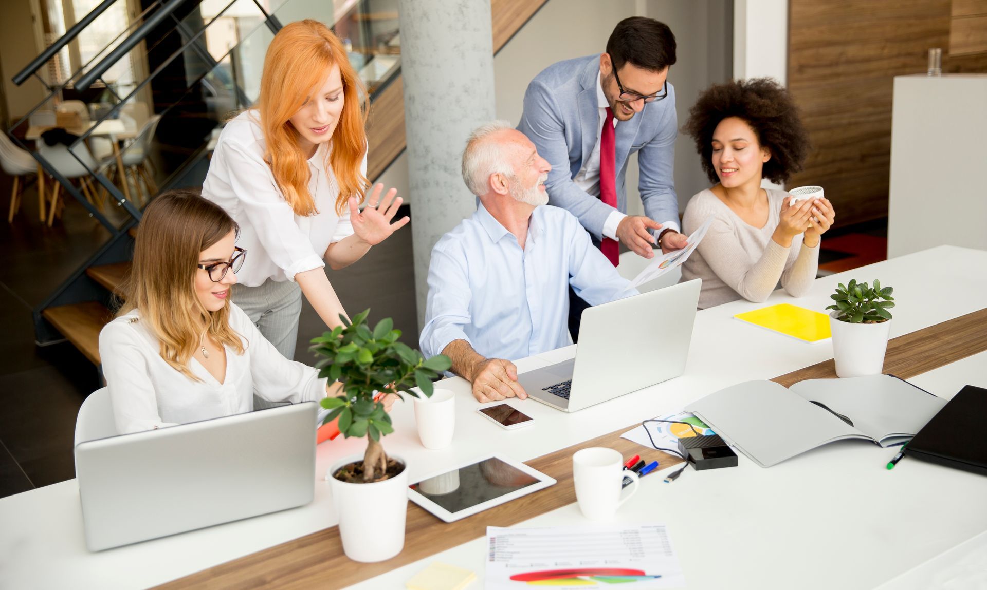 Group of people collaborating around a table with laptops. 