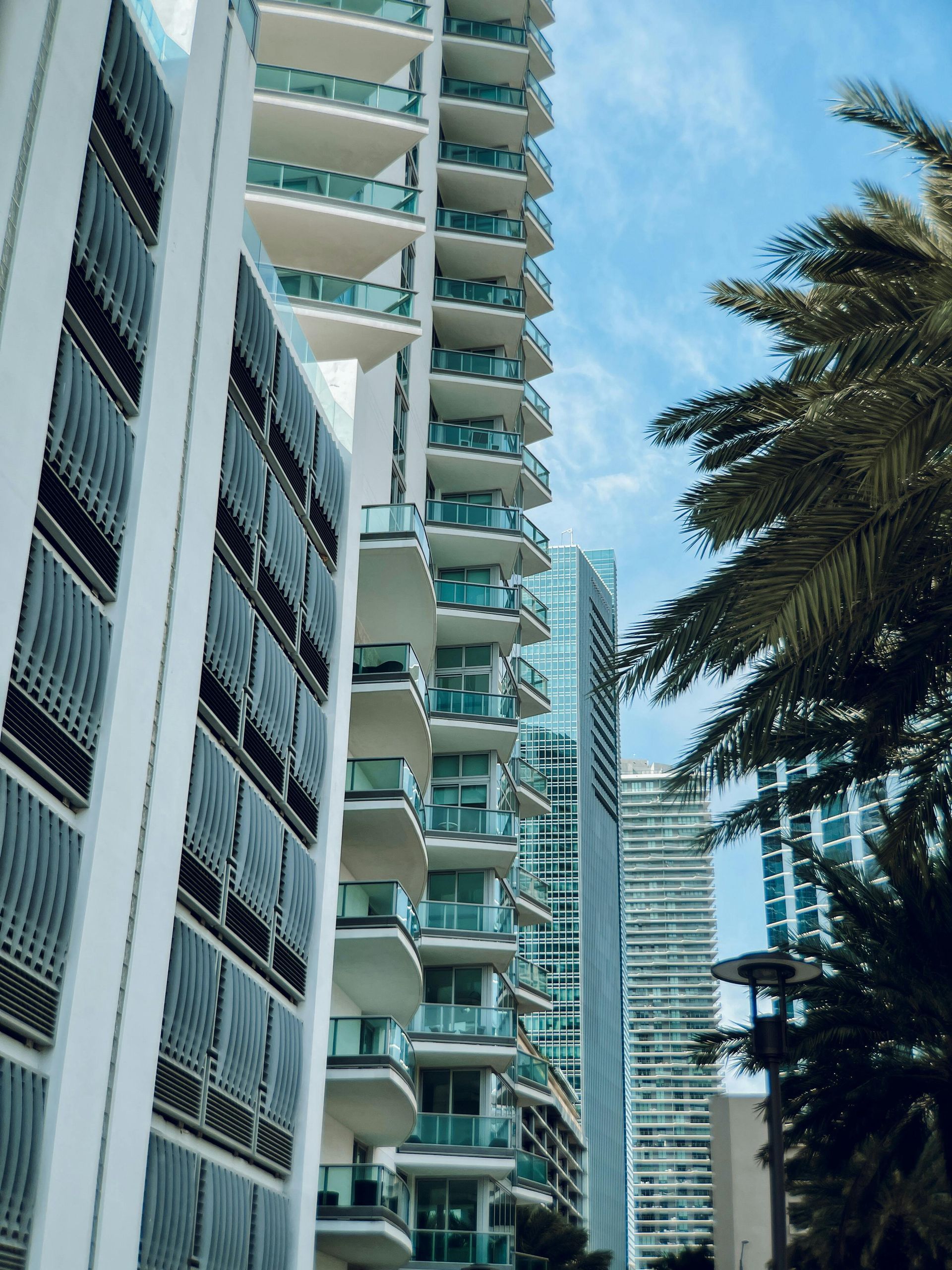 A tall building with balconies and a palm tree in the foreground