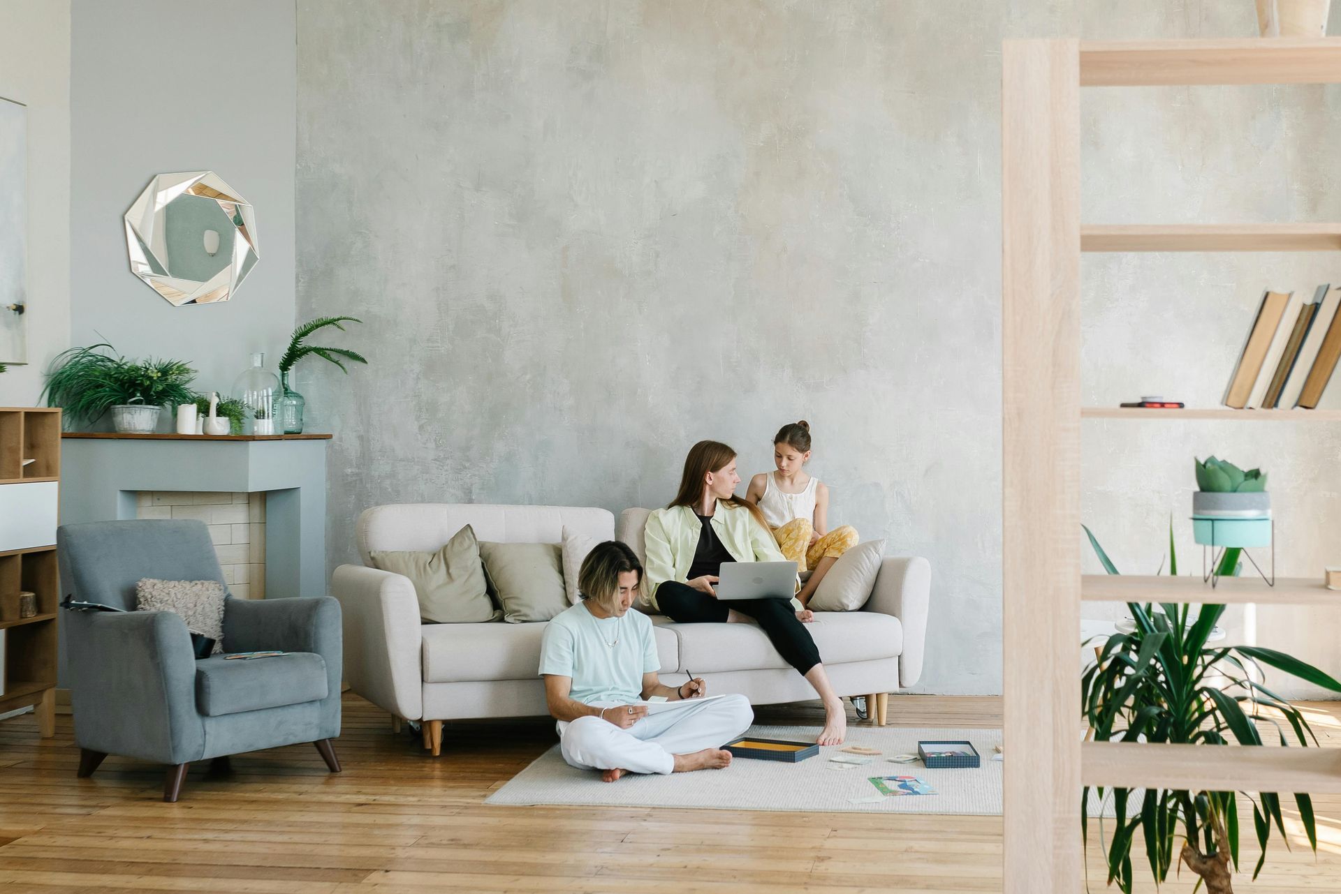 A family is sitting on a couch in a living room looking at a laptop.