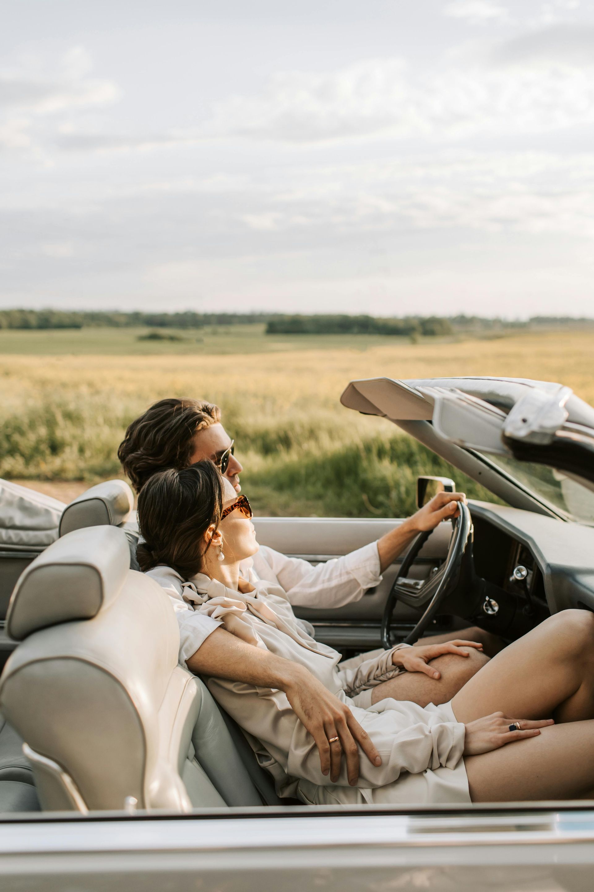 A man and a woman are sitting in a convertible car.