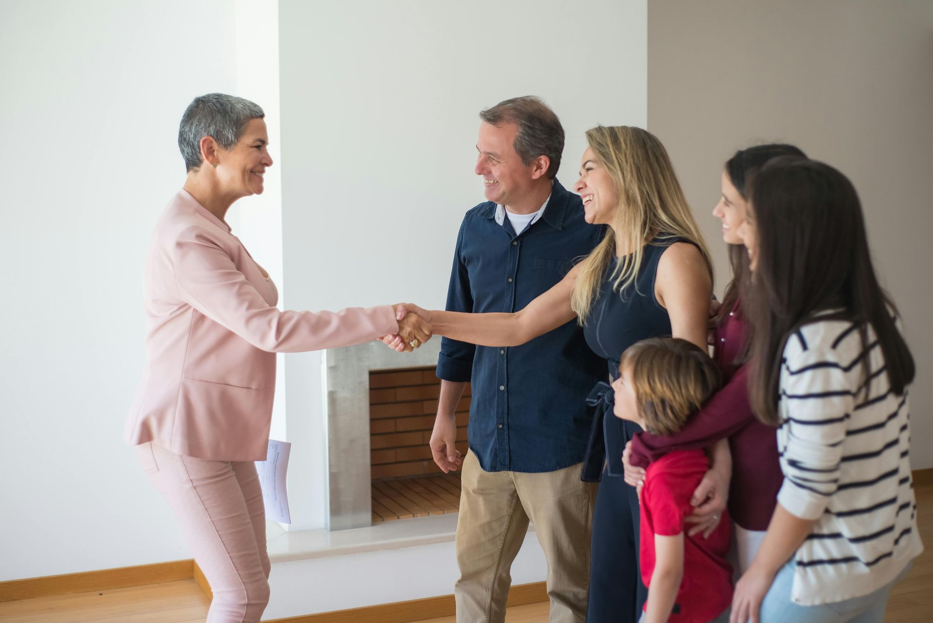 A woman is shaking hands with a family in a living room.