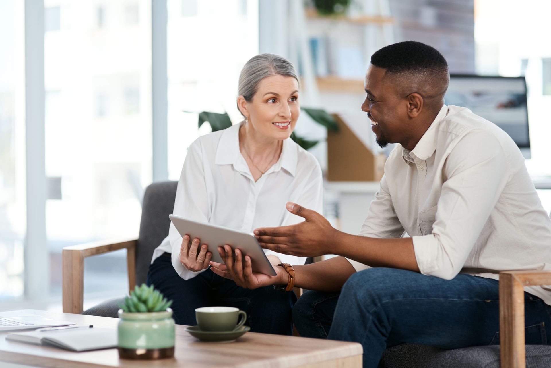 Woman and man in an office setting looking at a tablet, having a discussion. 