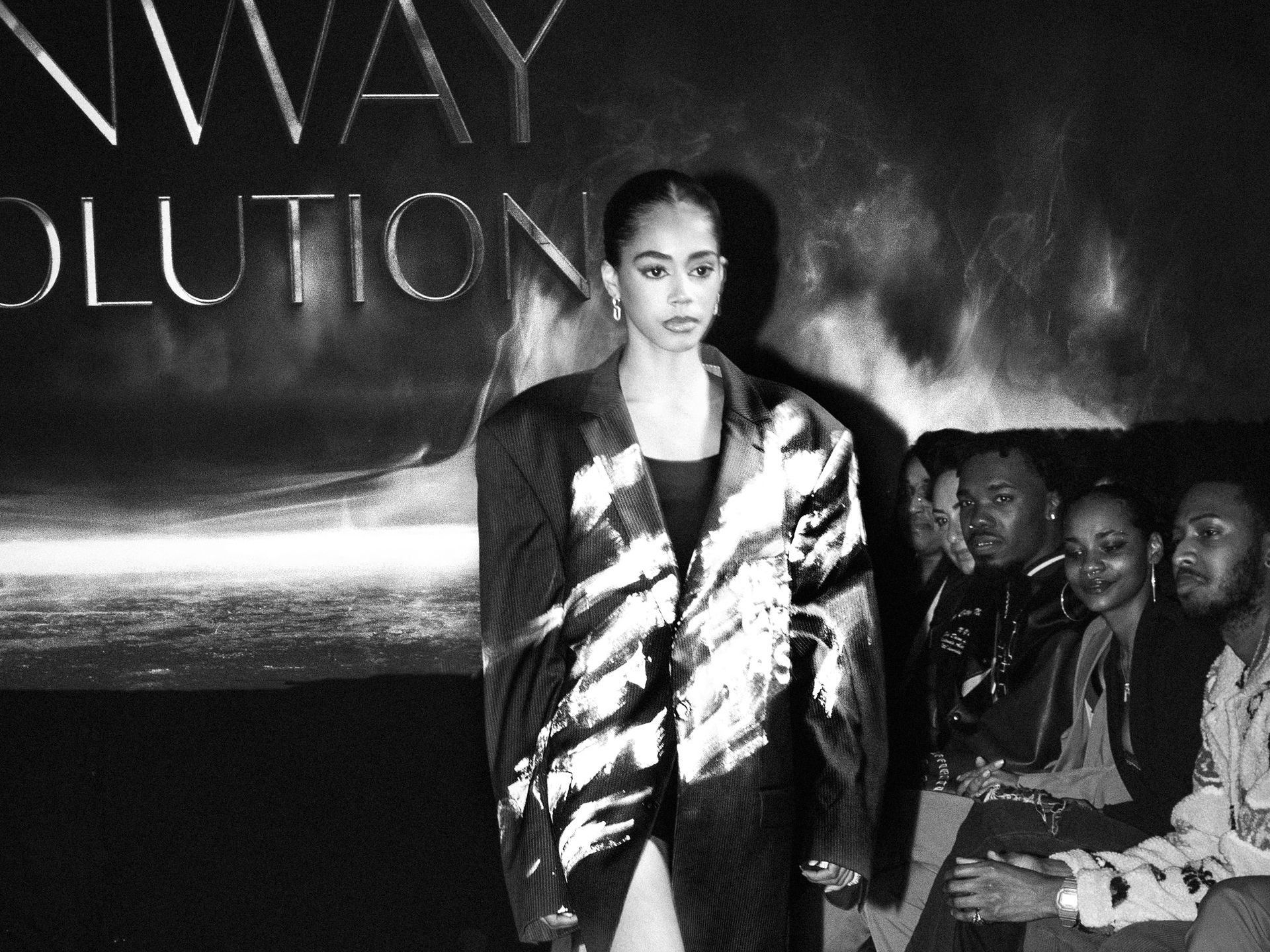 A black and white photo of a woman wearing a jacket and a ring on her finger.