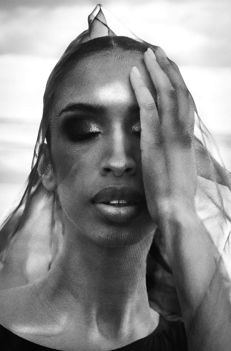 A woman wearing a black jacket and a denim shirt is sitting down.