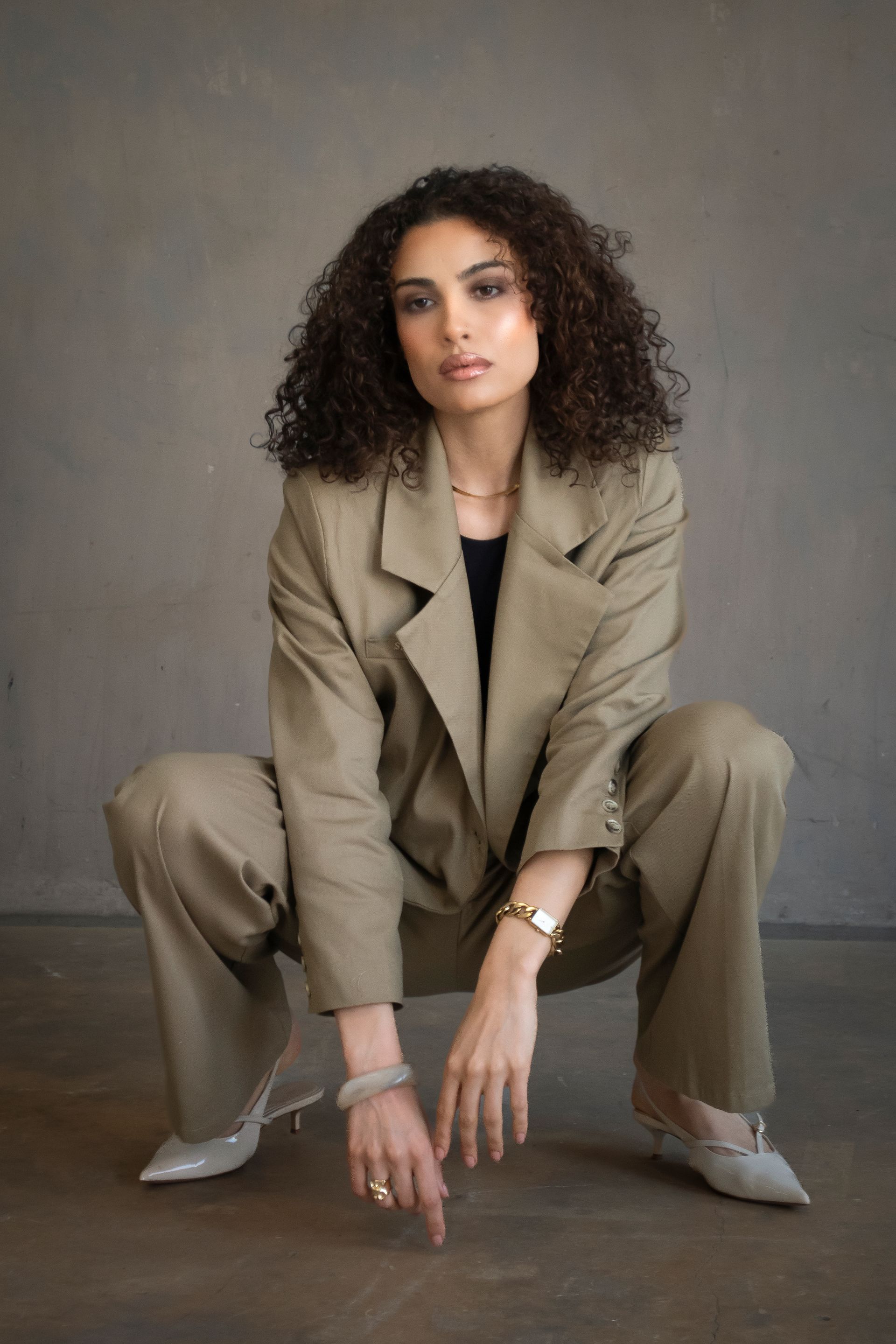 A woman with curly hair is wearing hoop earrings and a white top.